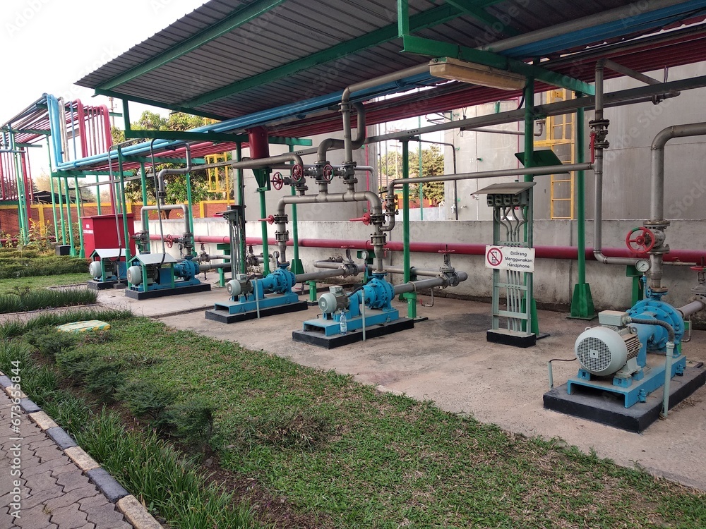 pump and electric motor installation in a factory with caution of Not using Cellphone in Indonesian Language