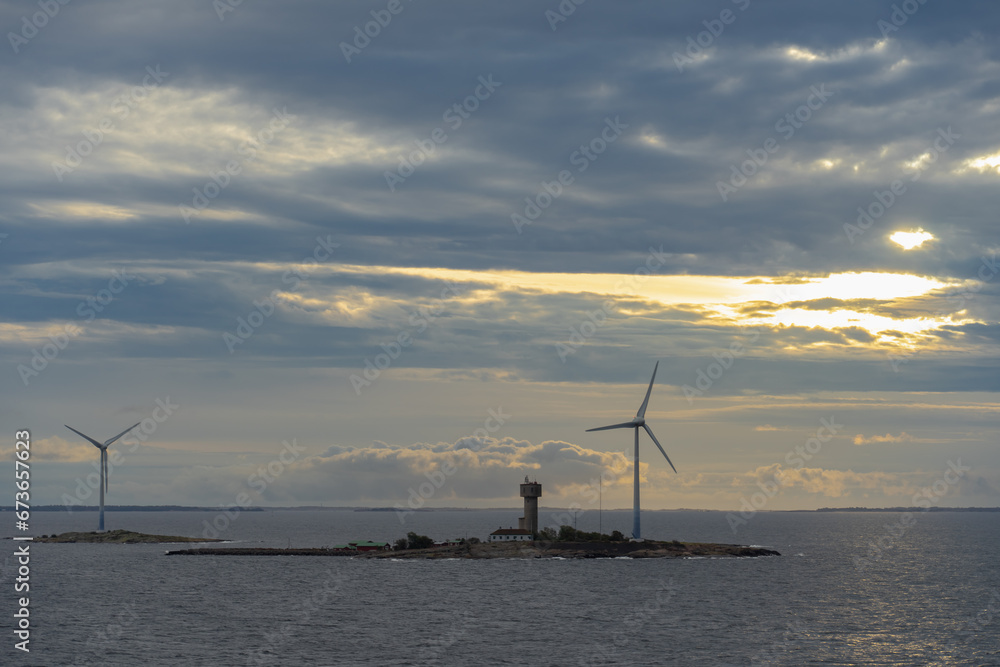 Small island with wind generators and buildings at sunrise in Åland islands.