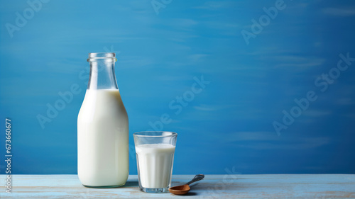 Bottle of milk and glass of milk on wooden table with blue background