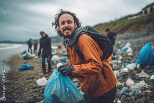 Man volunteer smiling looking at a camera picking up a plastic litter on a beach. photo