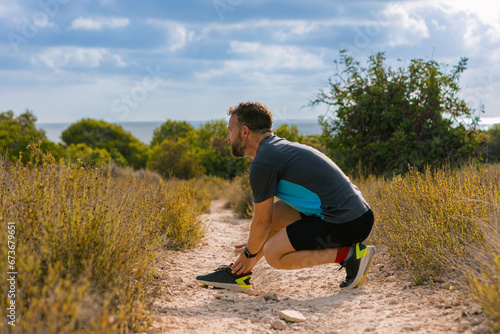 male runner holding a leg suffering from a sprained ankle muscle. Injured athlete during intense training. Concept of health and sport