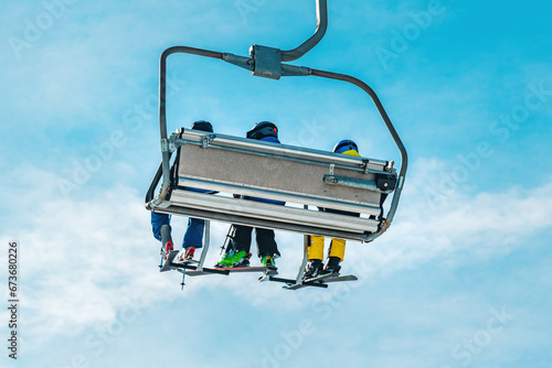 Unrecognizable skiers sitting on ski chairlift in winter