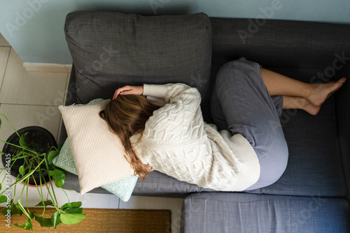 Woman with stomach cramp sleeping on sofa at home photo