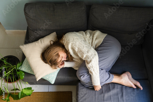 Woman with stomachache sleeping on sofa at home photo
