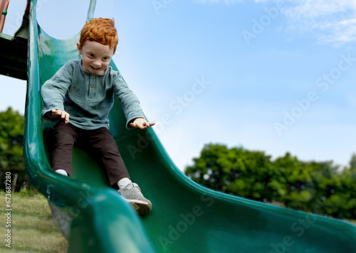 Excited boy playing on slide at playground photo