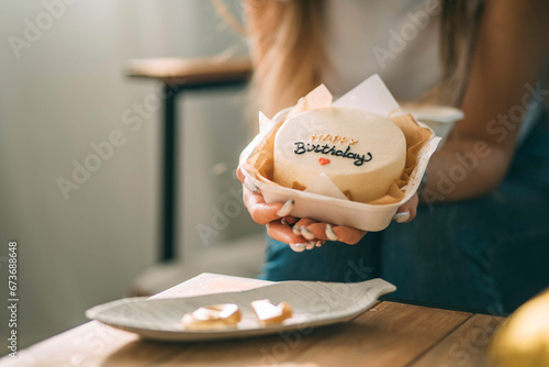 Young woman holding birthday cake in hand at home photo
