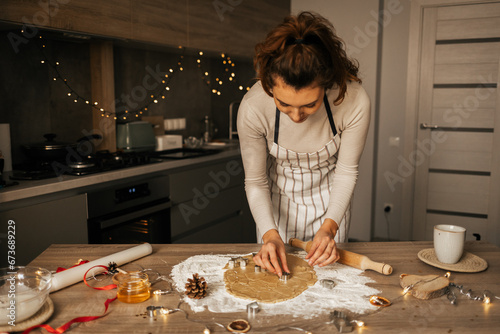 Happy caucasian carly woman cooking during winter holidays in cozy home kitchen, beautiful lady make traditional christmas gingerbread cookies on xmas day