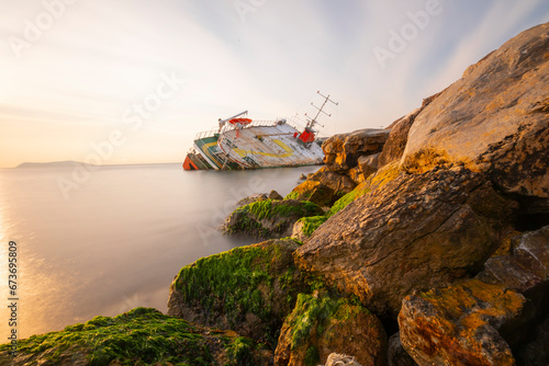 Sunken ship washed up on the seaside, sunset.
