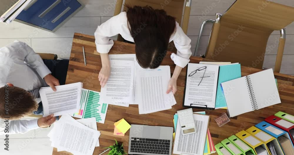 Man and woman workers sort through documents nervously looking for required file at table in company office. Workflow and lost report