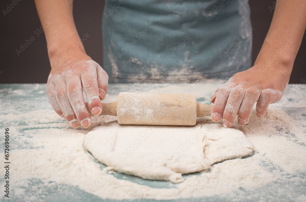 Baker rolls out dough for pizza, flatbread or pastry with rolling pin, prepare ingredients for food, baking for holidays
