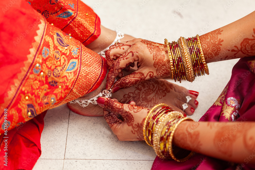 Indian Wedding Ceremony Concept. An Indian bride gets her silver anklets put on by another woman.