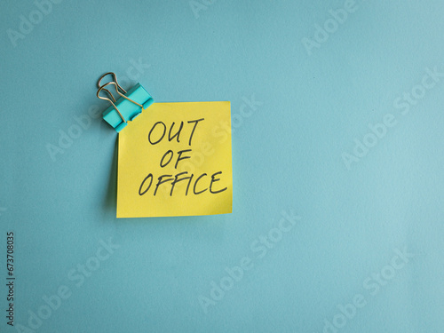 Out of office, message on yellow paper and blue background.