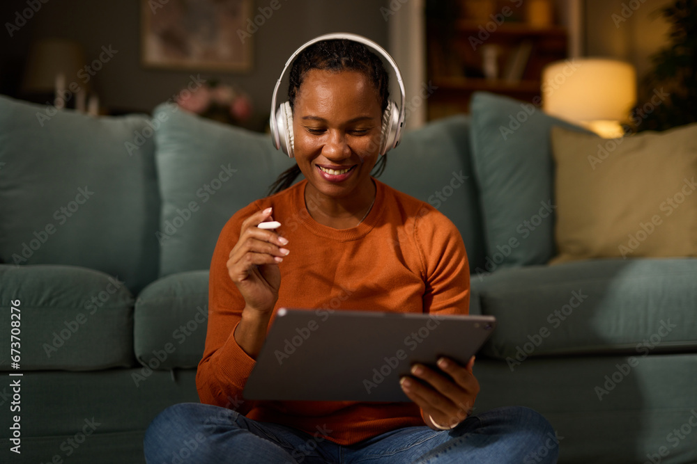 Woman with headphones using tablet and digitized pen at home Woman with headphones using tablet and digitized pen at home