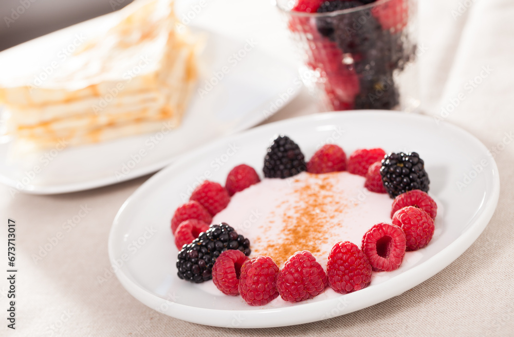 Breakfast of raspberries and blackberries with yogurt and pancakes on table Breakfast of raspberries and blackberries with yogurt and pancakes on table