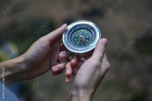 Cropped shot of female traveller using compass to navigate during hiking in forest