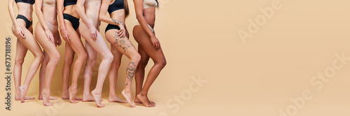 Fotografie Cropped image of different women, legs with different skin color and body shapes standing in underwear against beige studio background
