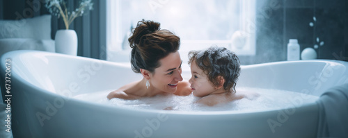 Mother taking a bath with her infant child in the bathtub photo