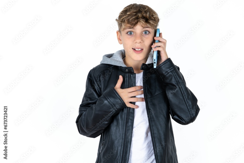 Smiling caucasian kid boy wearing black jacket talks via cellphone, enjoys pleasant great conversation. People, technology, communication concept Smiling caucasian kid boy wearing black jacket talks via cellphone, enjoys pleasant great conversation. People, technology, communication concept