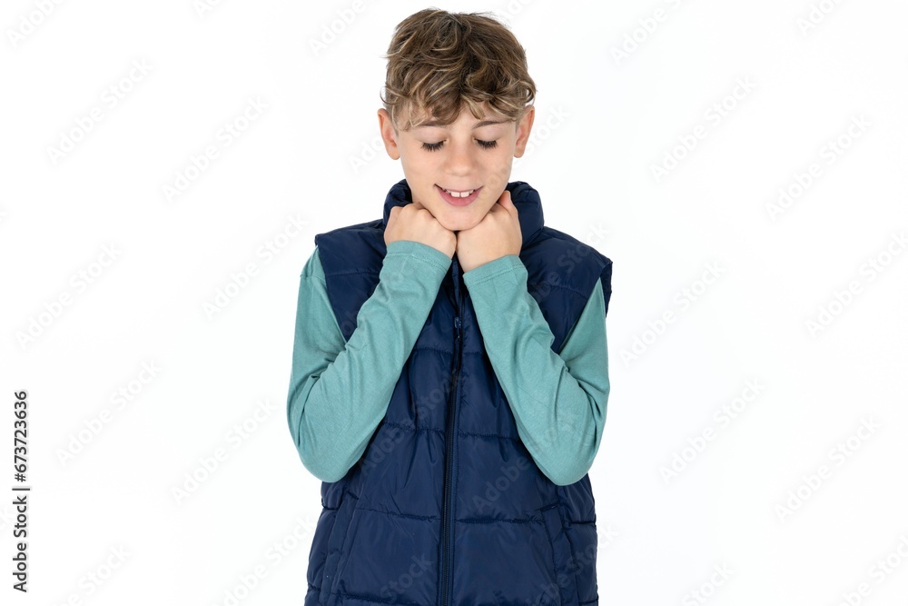 Cheerful caucasian kid boy wearing blue vest has shy satisfied expression, smiles broadly, shows white teeth, People emotions Cheerful caucasian kid boy wearing blue vest has shy satisfied expression, smiles broadly, shows white teeth, People emotions