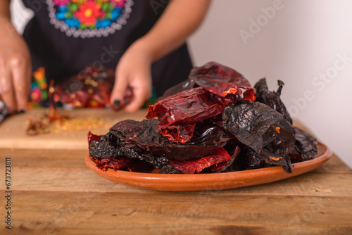 Ancho chili and guajillo chili in a clay dish on a wooden table. Chilies prepared to make red sauce. photo