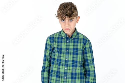 caucasian kid boy wearing plaid shirt depressed and worry for distress, crying angry and afraid. Sad expression.