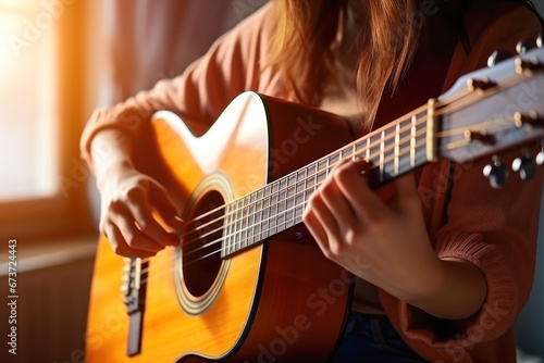 Close-up of a young woman who holds a guitar in her hands at home