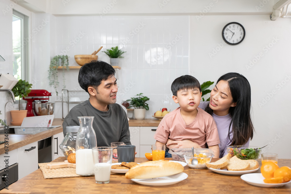 happy family together. Asian parent eating breakfast with little son in the kitchen. happy family together. Asian parent eating breakfast with little son in the kitchen.