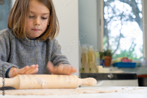 Boy stretching a pizza dough with a rolling pin