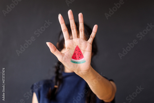 Woman showing hand painted with slice of watermelon to the camera. Symbol of support for Palestine