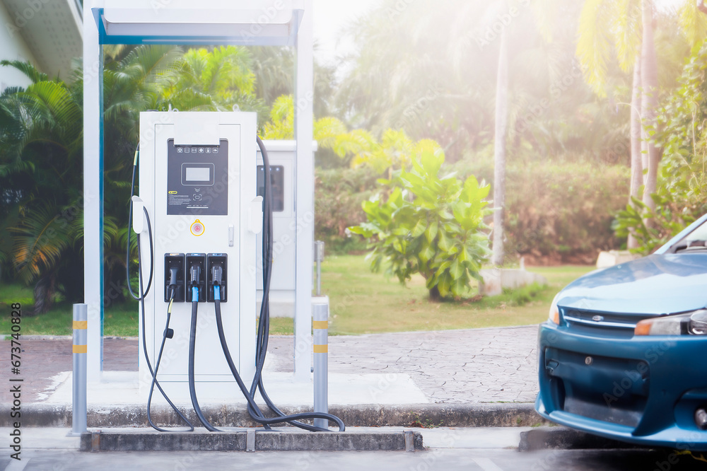 Outdoor electric vehicle filling station next to a green park. Outdoor electric vehicle filling station next to a green park.