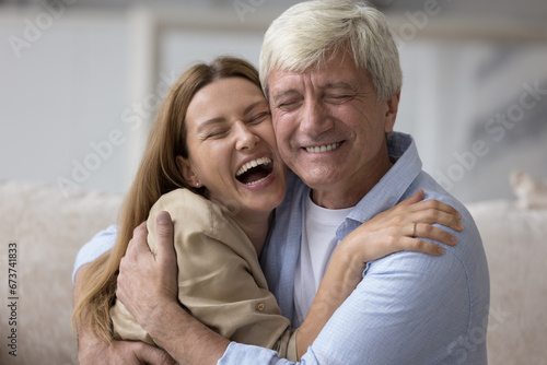 Happy grey haired senior daddy embracing beautiful adult daughter child, looking at camera, smiling, laughing, enjoying leisure, close relationship, affection. Family head shot portrait