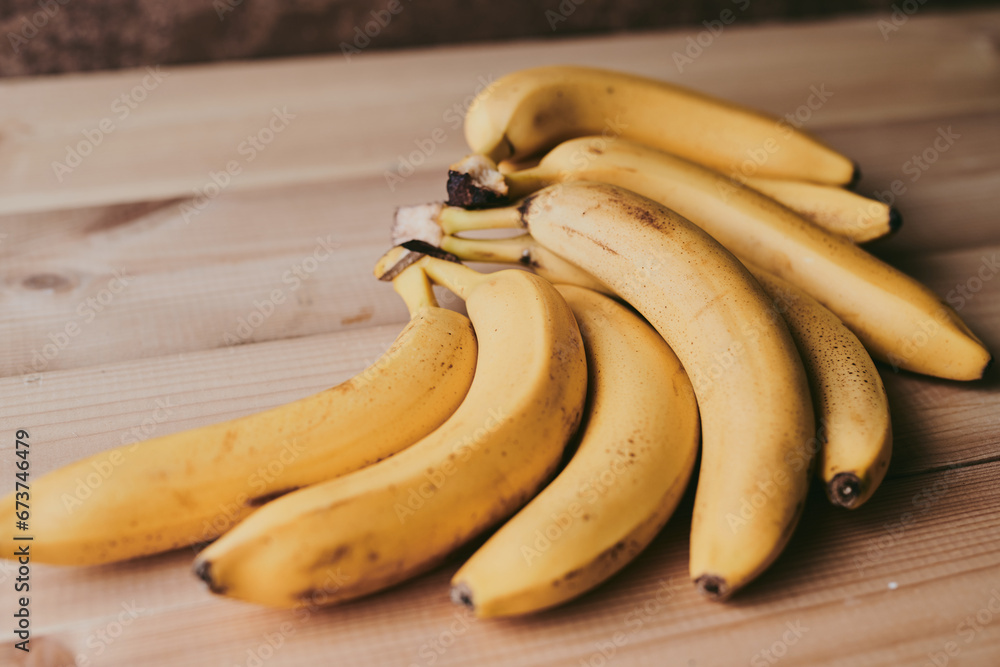 Close-up of a bunch of bananas on a wooden kitchen table background Close-up of a bunch of bananas on a wooden kitchen table background
