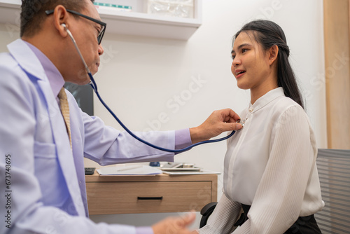 Doctor using stethoscope to listen heartbeat of elderly patient. young Asian woman to detect abnormal heart rates from insufficient rest.	 photo