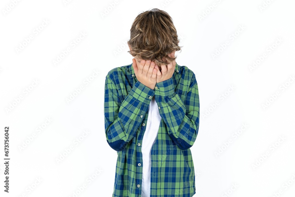 Caucasian teen boy covering her face with her hands, being devastated and crying. Sad concept Caucasian teen boy covering her face with her hands, being devastated and crying. Sad concept