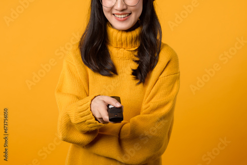 A content young woman in a yellow sweater holding a remote control, enjoying leisure time in her living room. photo