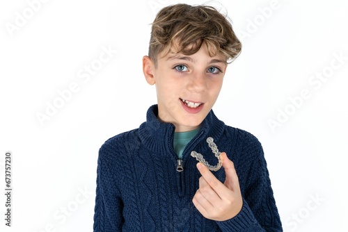 Caucasian teen boy holding an invisible aligner ready to use it. Dental healthcare and confidence concept.
