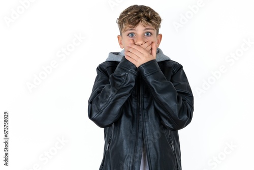 Stunned Caucasian teen boy covers both hands on mouth, afraids of something astonishing