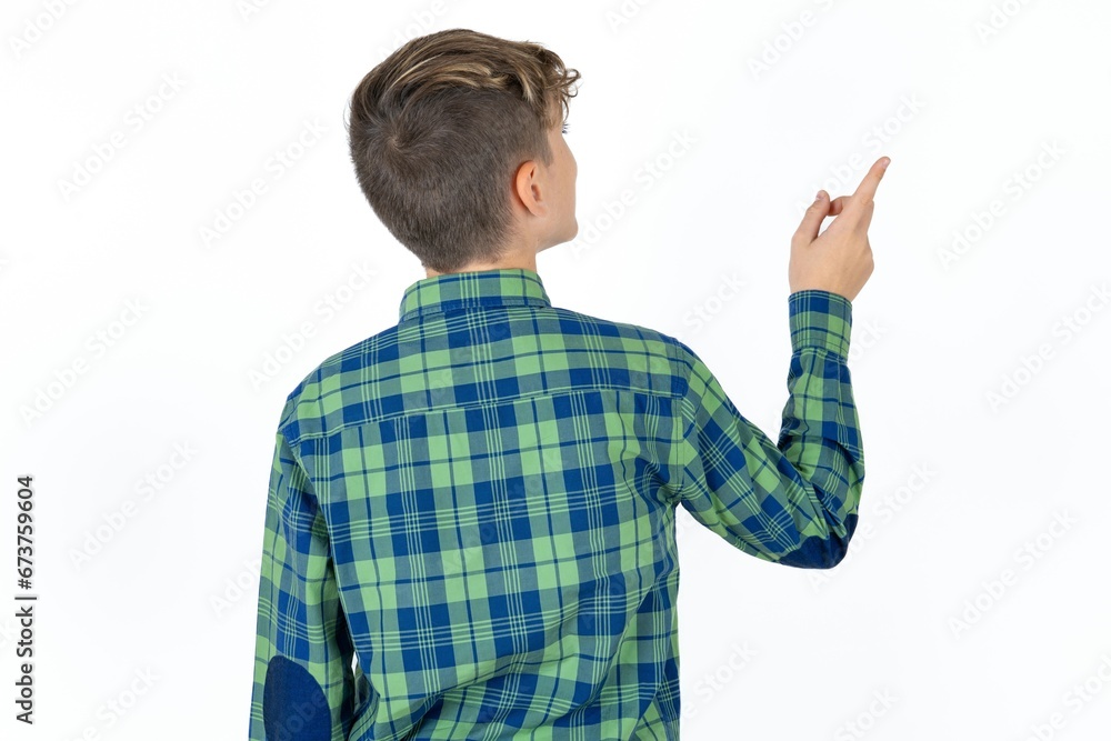 Caucasian teen boy wearing plaid shirt pointing to object on copy space, rear view. Turn your back Caucasian teen boy wearing plaid shirt pointing to object on copy space, rear view. Turn your back