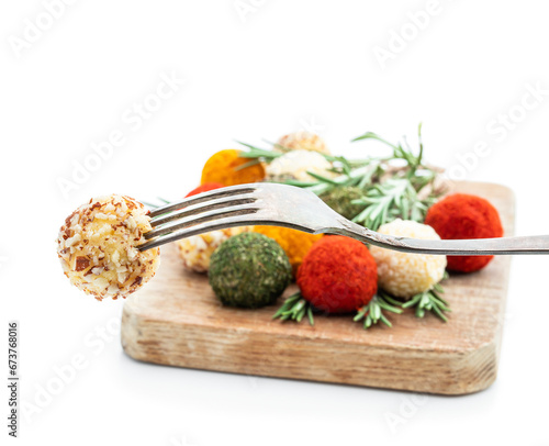 Cheese balls covered with various spices and nuts decorated with rosemary sticks isolated on white