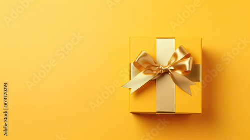 Gift box with golden satin ribbon and bow on yellow background.Holiday gift with Birthday or Christmas present, flat lay, top view, happy mother day copy space