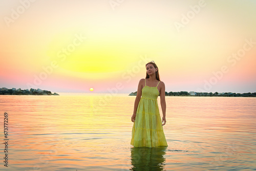 Young woman standing in water at sunset