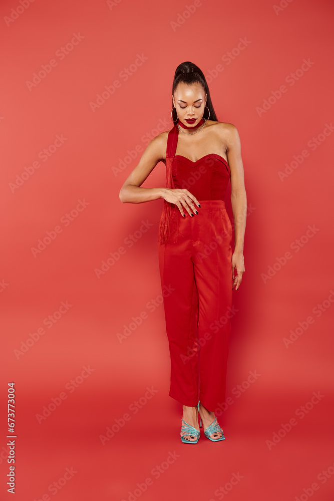 full length of beautiful african american model in strapless top and pants posing on red background full length of beautiful african american model in strapless top and pants posing on red background