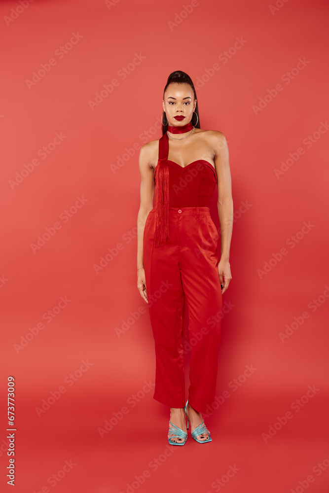 full length of attractive african american model in strapless top and pants posing on red background full length of attractive african american model in strapless top and pants posing on red background