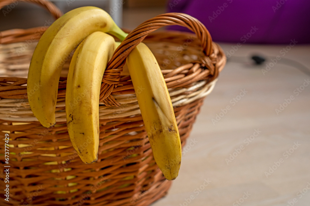 bunch of yellow bananas lie in a rattan basket