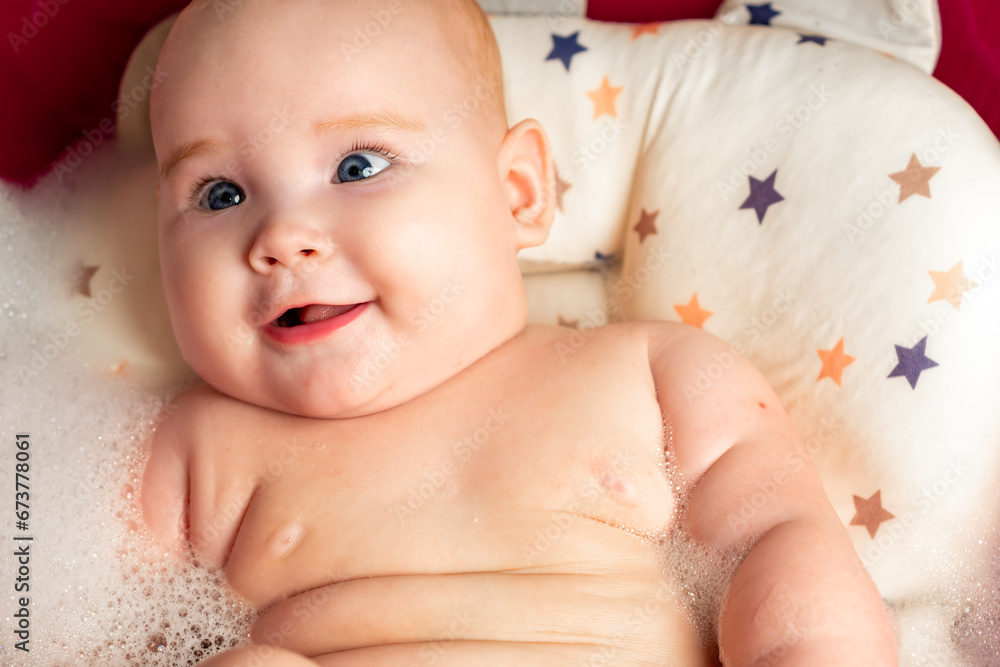 Newborn baby taking a bath in a red bathtub with foam Newborn baby taking a bath in a red bathtub with foam