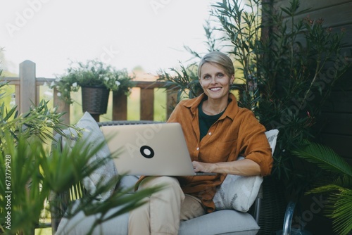 Foto Woman working in the garden, with laptop on legs