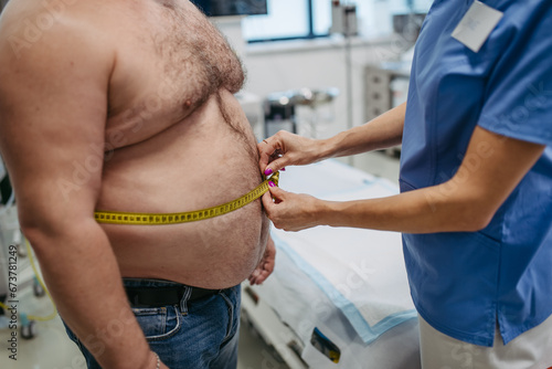 Obraz na plátně Female doctor measuring waist of overweight patient using tape measure