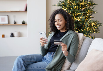 Young woman ordering gift during Christmas holiday at home using smartphone and credit card. Shopping online during holidays, internet banking, store online, spending money, winter holiday concept