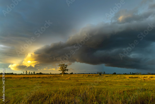 Photo of Super storm with sun light , Dark sunset sky and dramatic black cloud before rain.rainy storm over rice fields,countryside Thailand,ASIA.
