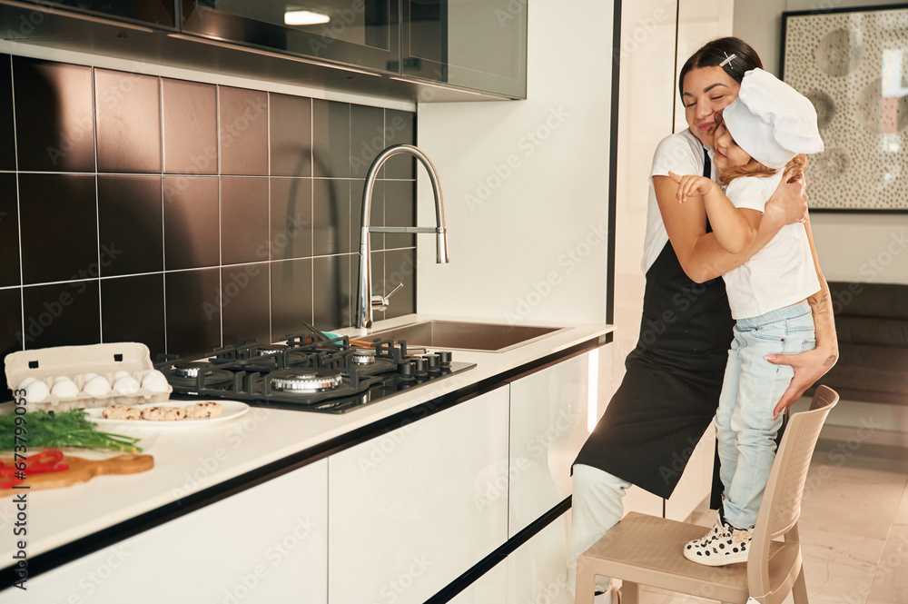Near the sink. Mother with her daughter are preparing food on the kitchen Near the sink. Mother with her daughter are preparing food on the kitchen